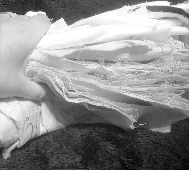 A hand holding a pile of embroidered fabric