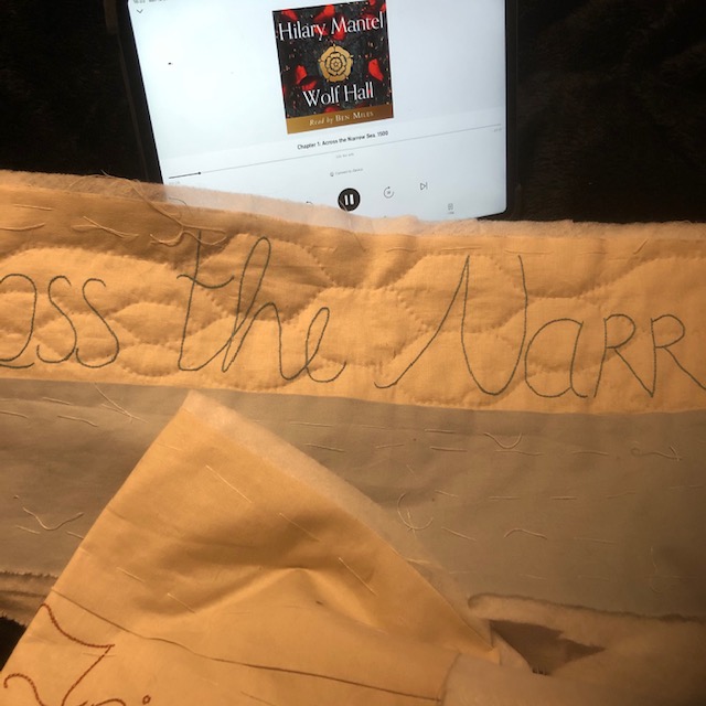 An ipad with the audio book of Wolf Hall and a section of quilting