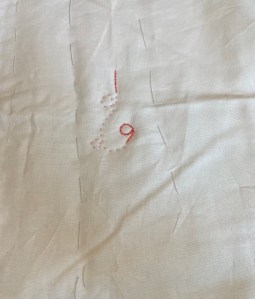 White fabric with some quilting in chain and running stitch in orange thread